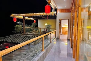 A hotel interior with a traditional thatched roof structure, a glass railing, and a modern interior design.