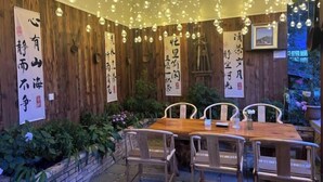 A dining area with a wooden table and chairs, surrounded by wooden walls and hanging spherical lights.
