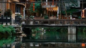 A traditional building with a waterway in front, wooden balconies, and a sign with Chinese characters.