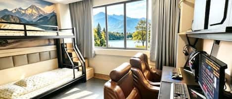 A room with bunk beds, a desk with a computer, and a view of mountains through the window.