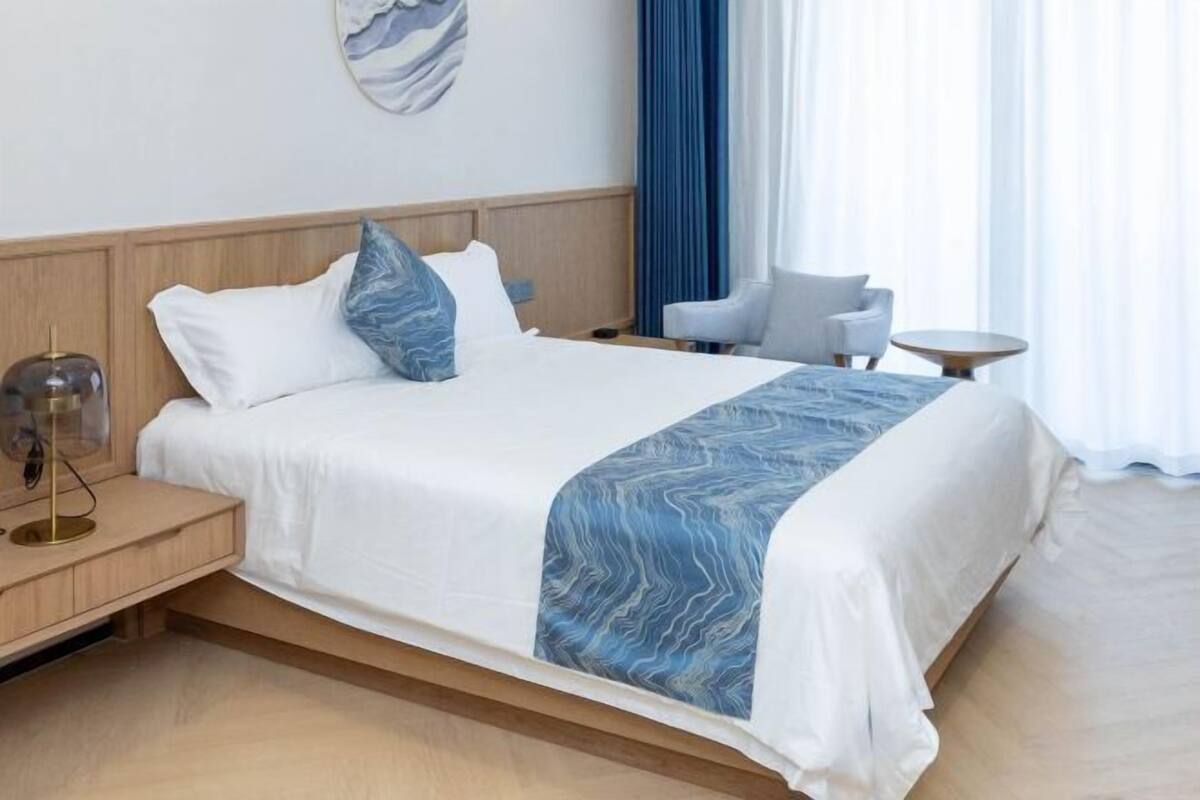 A hotel room with a bed, bedside table, chair, and a small round table.