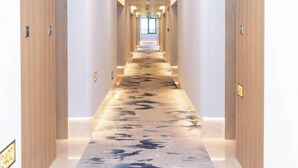 A long, narrow hallway with wooden doors on either side and a patterned carpet. - Yangzi Hotel (Nanjing)