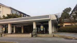 A building with a covered entrance, stone lion statues, and a large circular emblem. - Yangzi Hotel (Nanjing)