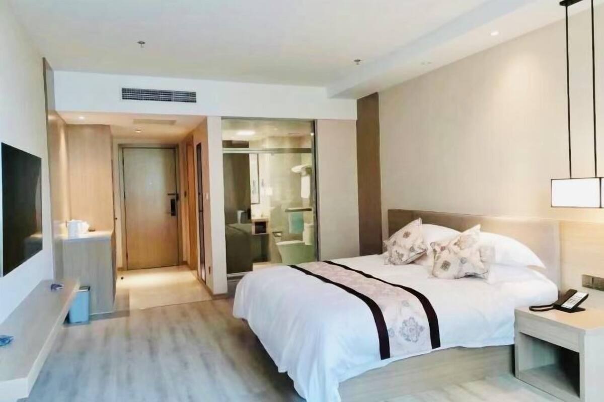 A modern hotel room with a bed, bedside table, and a TV.
