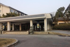 A building with a covered entrance, stone statues, and a sign. - Yangzi Hotel (Nanjing)