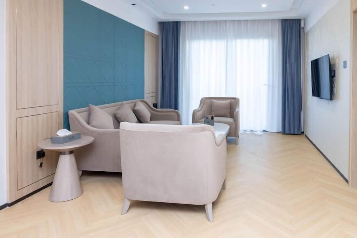 A modern hotel room with a sofa, armchair, and a small side table.