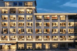 Un hotel de varios pisos con un diseño moderno, que presenta una fachada uniforme con ventanas regularmente espaciadas y un techo plano.