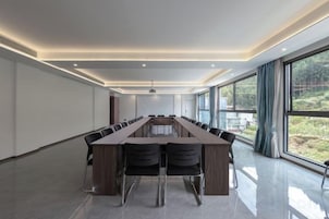 Un salón de conferencias con una larga mesa, sillas y vistas amplias a través de grandes ventanales.