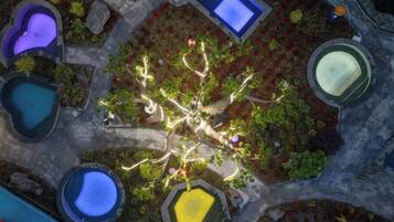 An aerial view of a landscaped area with multiple water features, including pools and fountains, arranged around a central tree.