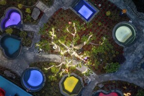 An aerial view of a landscaped area with multiple water features, including pools and fountains, arranged around a central tree. - Washanhu Hot Spring Hotel (Hongya)