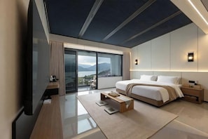 A modern hotel room with a large bed, a desk, and a view of the outdoors.