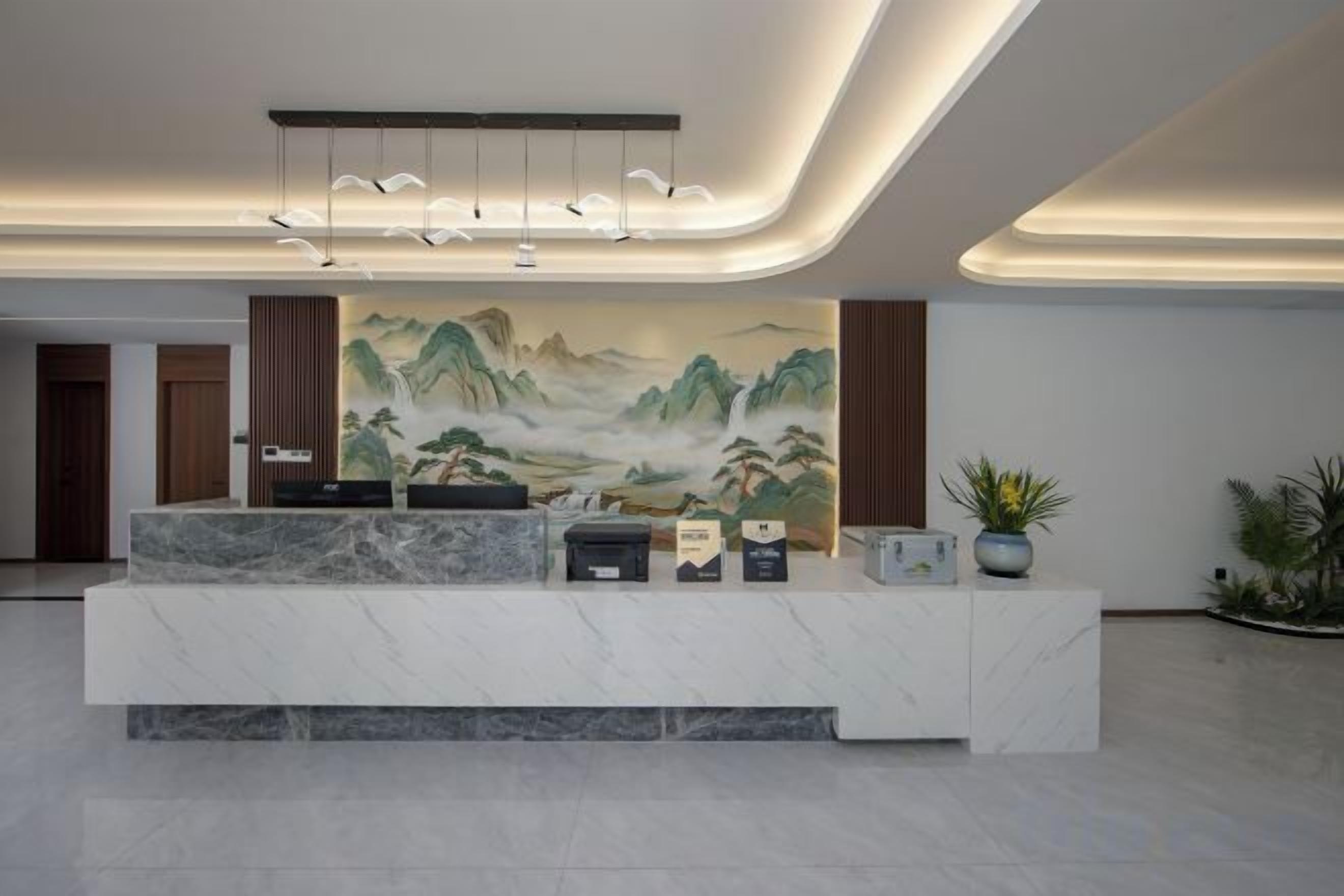 A reception area with a marble counter, a large landscape painting, and a modern light fixture.