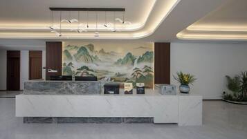 A reception area with a marble counter, a large landscape painting, and a modern light fixture.