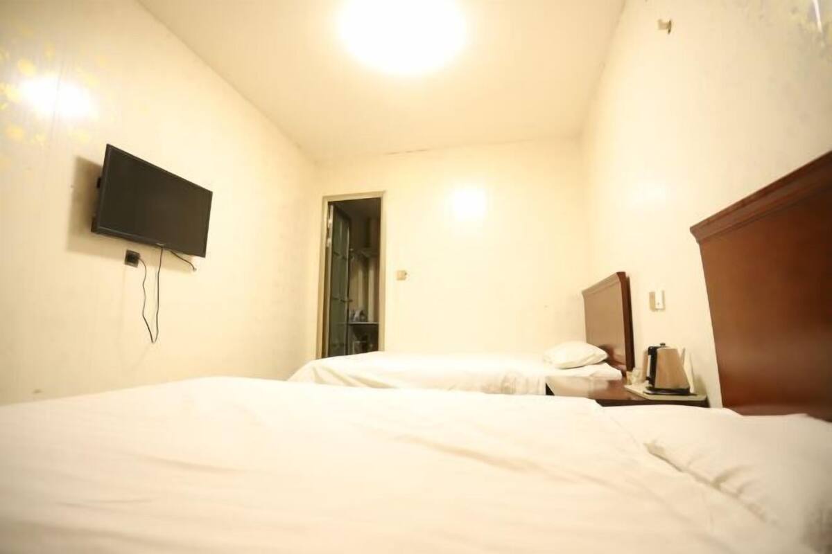 Een hotelkamer met twee bedden, een flatscreen televisie aan de muur en een houten hoofdbord.