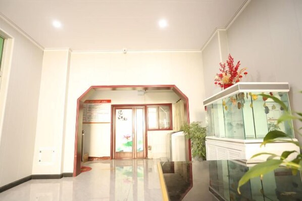A hotel lobby with a reception desk, a glass display case, and a plant.