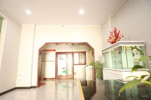Un hall de hotel con mostrador de recepción, una vitrina de vidrio y una planta.