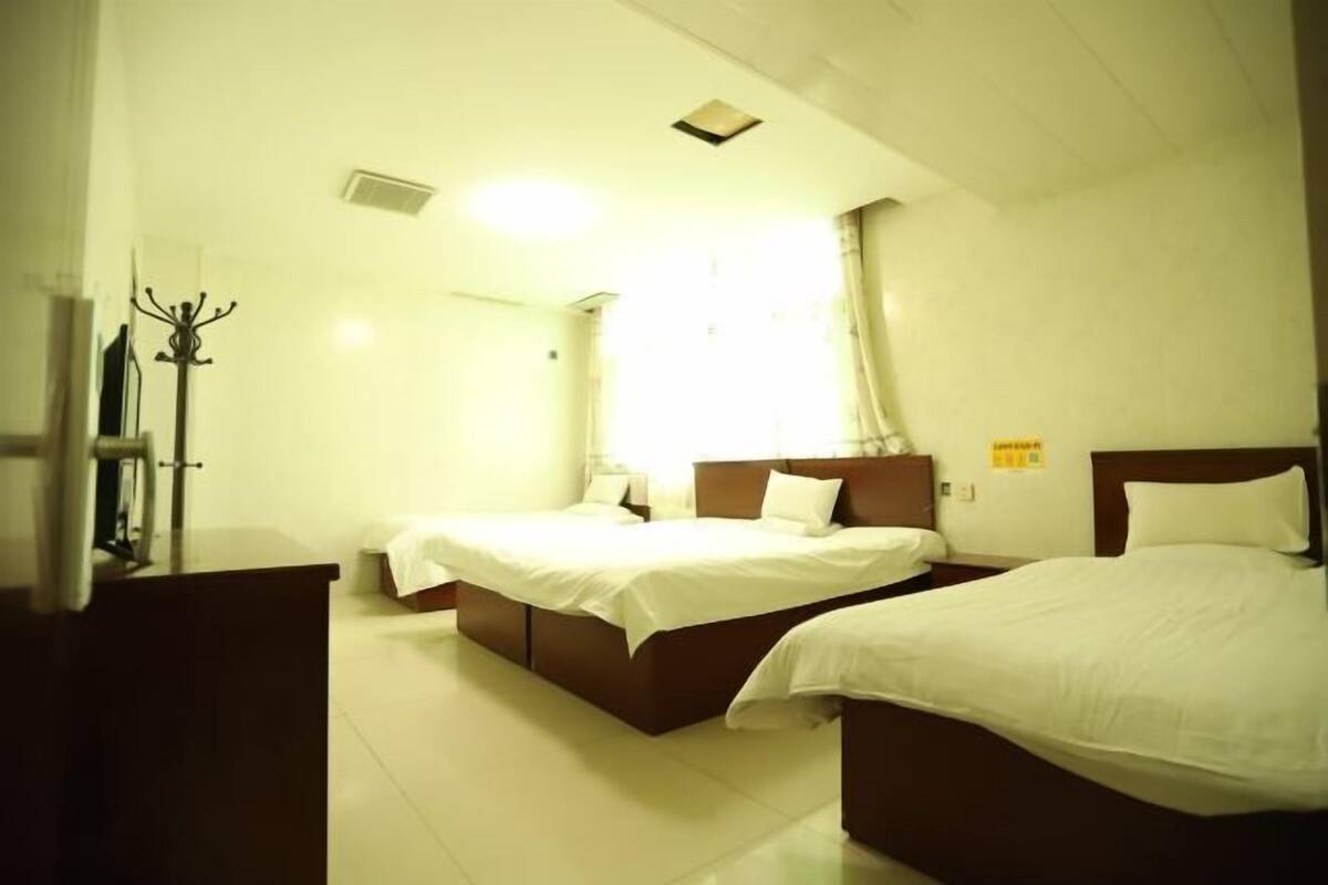 Een hotelkamer met twee bedden, een nachtkastje, een lamp en een kapstok.