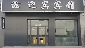 L’entrée d’un hôtel, avec une façade moderne, de grandes portes vitrées et une enseigne au-dessus de l’entrée.
