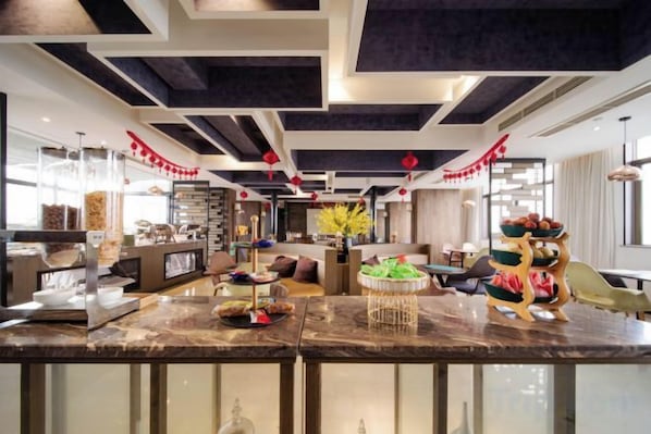 A modern hotel lobby with a marble reception desk, seating area, and decorative elements.