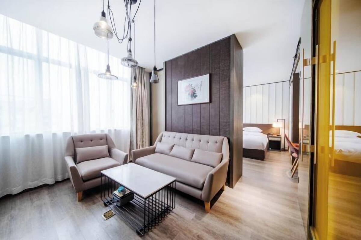 Une chambre d’hôtel moderne, équipée d’un canapé, d’un fauteuil et d’un lit.