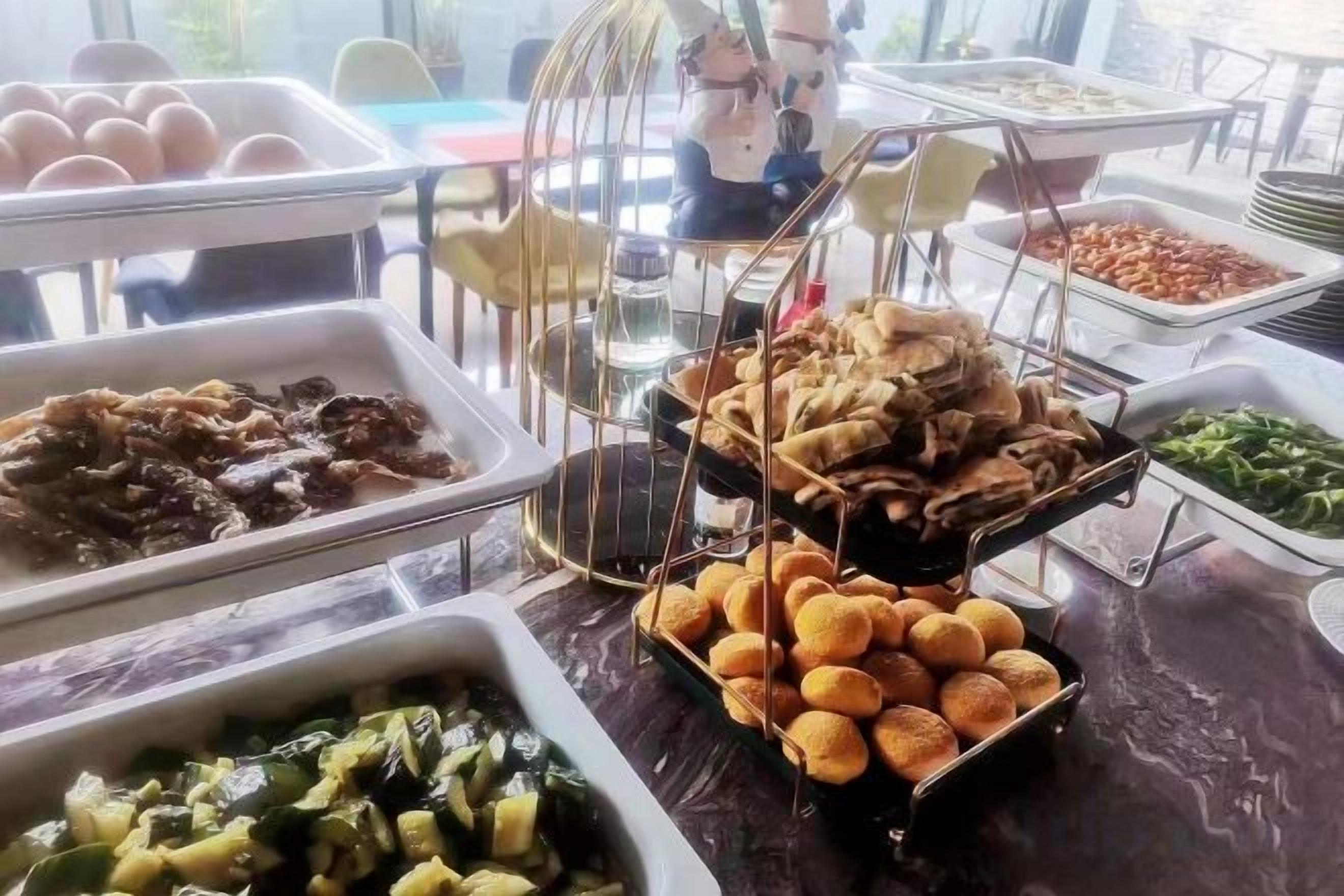 Une table de buffet garnie de divers plats et agrémentée d’une cage à oiseaux décorative.