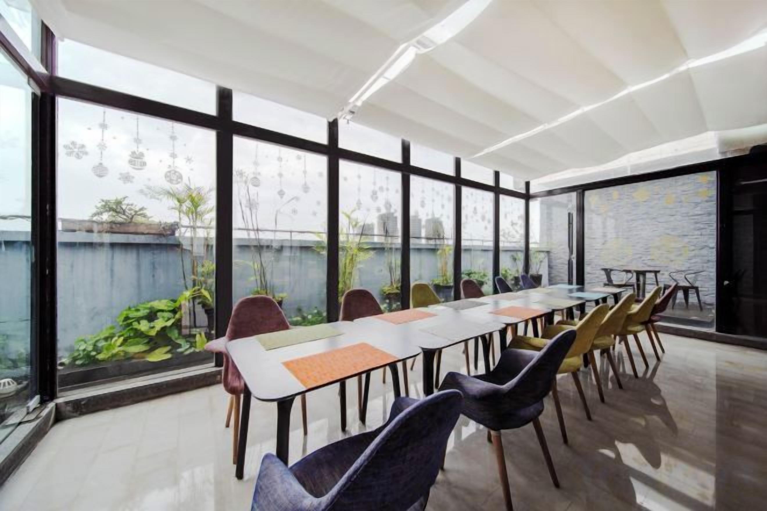 A conference room with a long table and chairs, large windows, and a view of greenery outside.