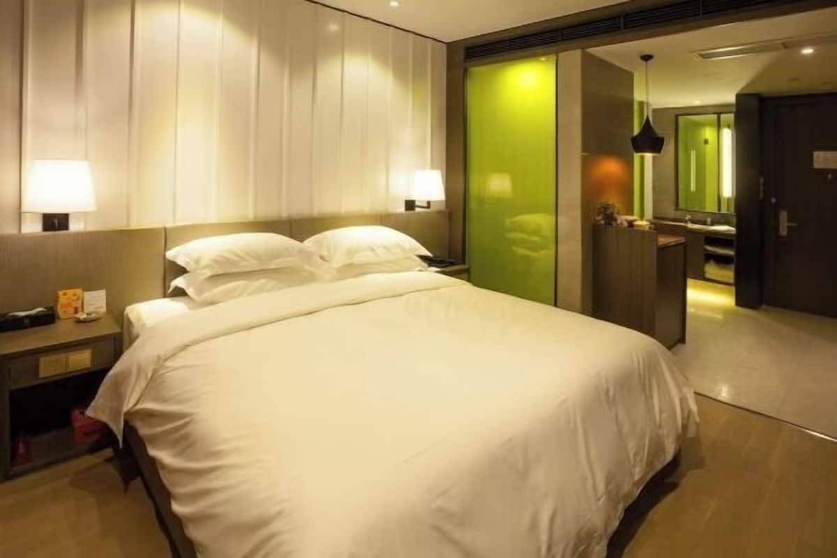 Une chambre d’hôtel avec un grand lit, des lampes de chevet, un miroir et une porte verte.