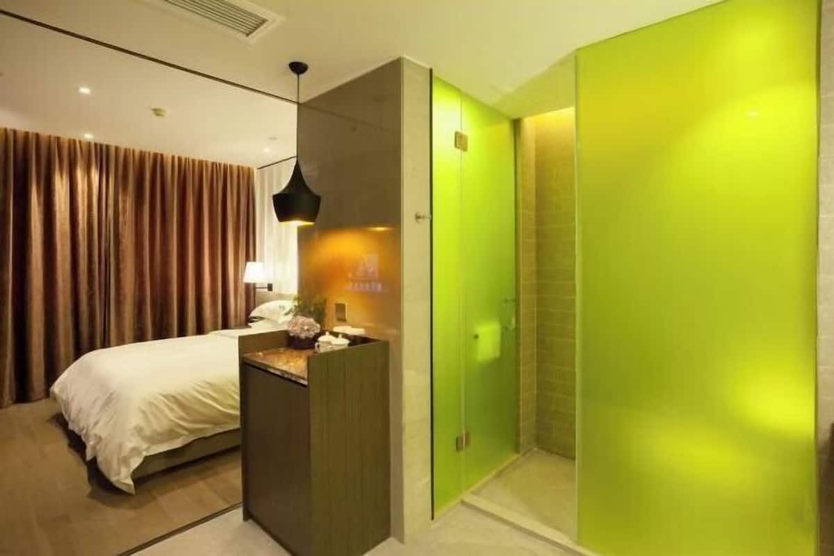 Une chambre d’hôtel avec un lit, un bureau, une porte verte et un espace douche.