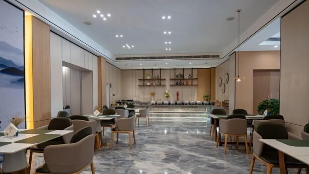 A modern dining area with marble flooring, wooden chairs, and tables arranged for guests. - Kunxing Century Hotel (Lotus Plaza) (Lianhua)
