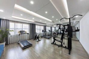 A modern gym with various exercise equipment, large windows, and a wooden floor. - Kunxing Century Hotel (Lotus Plaza) (Lianhua)