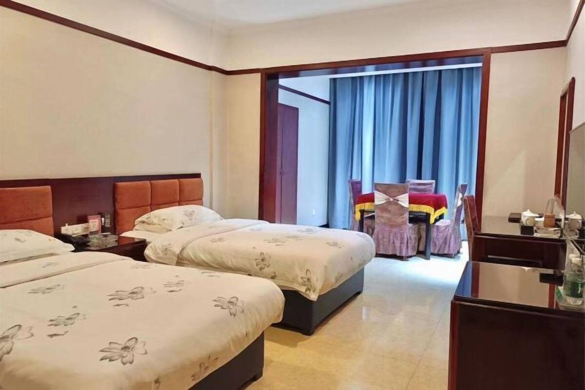 Habitació d'hotel amb dos llits, una taula de treball, una cadira i un armari.