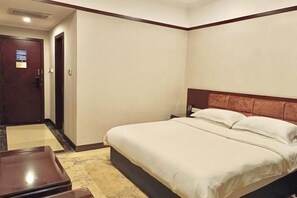 A hotel room with a bed, a nightstand, a wooden bench, and a door.