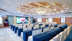A conference room with rows of tables and chairs, a large screen, and a modern ceiling design. - Kunxing Century Hotel (Lotus Plaza) (Lianhua)