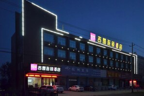 A hotel with multiple floors, illuminated signage, and a parking lot with cars. - Jichu hotel (Jingzhou ocean world store) (Jingzhou)