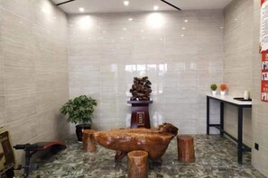 A room with a large wooden sculpture, a potted plant, and a small table with a vase. - Jichu hotel (Jingzhou ocean world store) (Jingzhou)