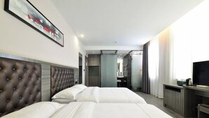 Une chambre d’hôtel avec deux lits, une télévision, un bureau et une salle de bain visible à travers une porte ouverte.