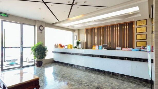 Un hall d’hôtel avec un sol en marbre, un comptoir d’accueil, une plante en pot et des certificats encadrés accrochés au mur.