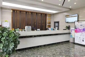 A hotel reception area with a marble counter, a digital screen, and a plant. - Jichu hotel (Jingzhou ocean world store) (Jingzhou)