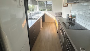 A modern kitchen with a refrigerator, stove, and sink. - Life by the sea! Enjoy tranquil views and all-day sun. (Kakanui)