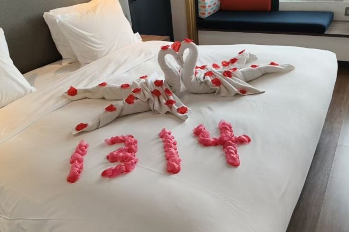 Un lit avec du linge de lit blanc et des motifs floraux roses.