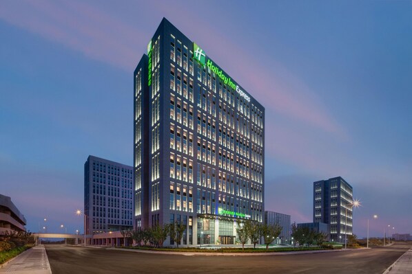 Un hotel de varios pisos con un llamativo letrero de 'Holiday Inn Express', ventanas amplias y un diseño arquitectónico moderno.