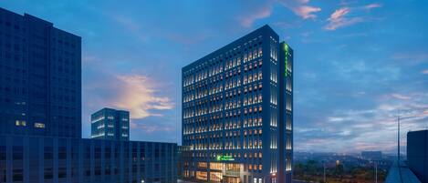 Een modern hotelgebouw met een glazen gevel, meerdere verdiepingen en een opvallende entree.