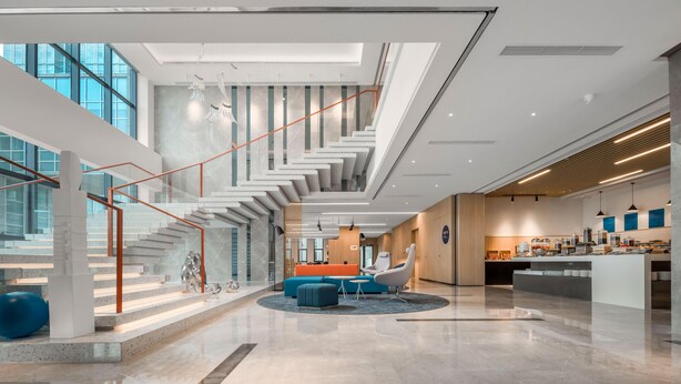 Un hall espacioso con una zona de estar central, una escalera y un área de cocina.