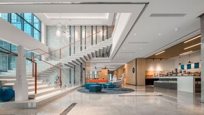 A spacious lobby with a central seating area, a staircase, and a kitchen area. - Holiday Inn Express Rongcheng Science And Technolo (Weihai)