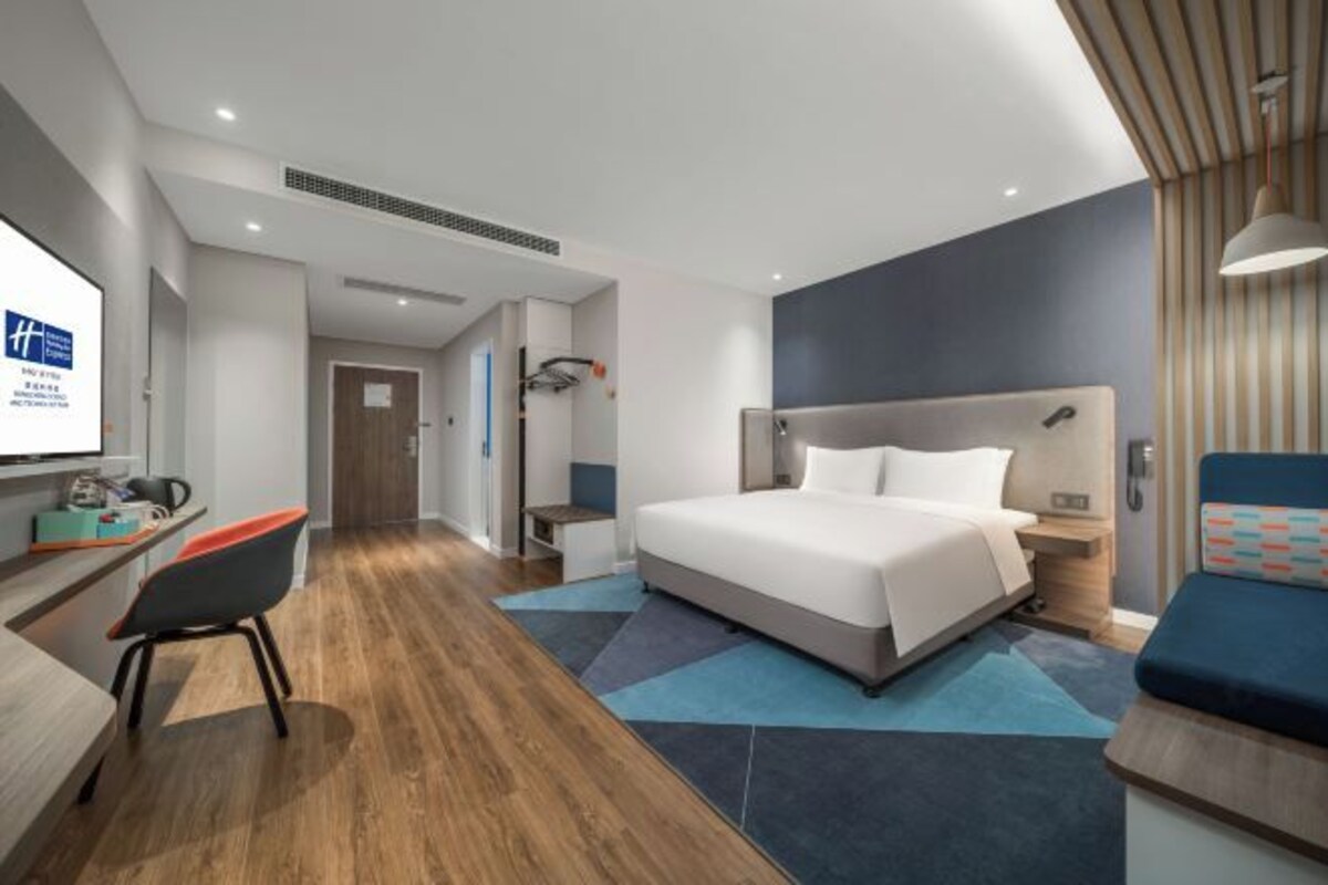 Camera d'albergo moderna con un letto grande, una scrivania con una sedia, una TV e un angolo relax.