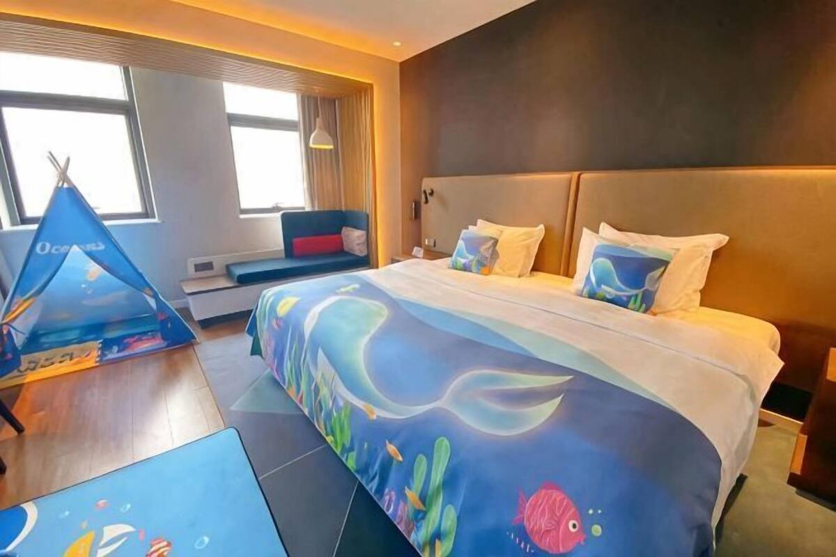 A hotel room with a bed, a window, a seating area, and a tent-like structure.