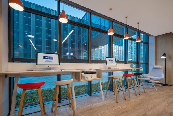 Un espacio de oficina moderno con ventanas amplias, escritorios, sillas e iluminación colgante.