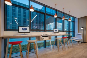 Un espacio de oficina moderno con ventanas amplias, escritorios, sillas e iluminación colgante.