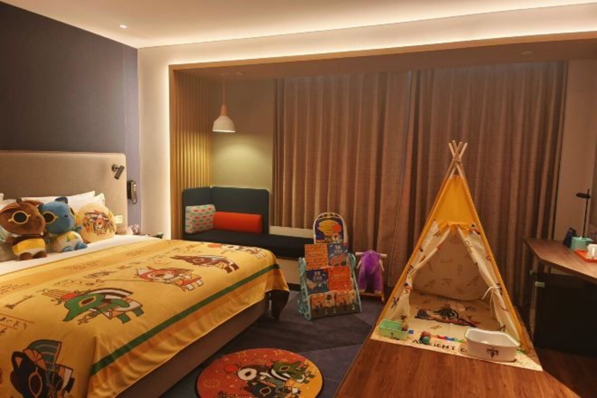 Una camera d'albergo con un letto, un tavolino, una sedia, una finestra con tende e una tenda.