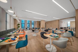 A modern dining area with long tables, chairs, and pendant lighting. - Holiday Inn Express Rongcheng Science And Technolo (Weihai)